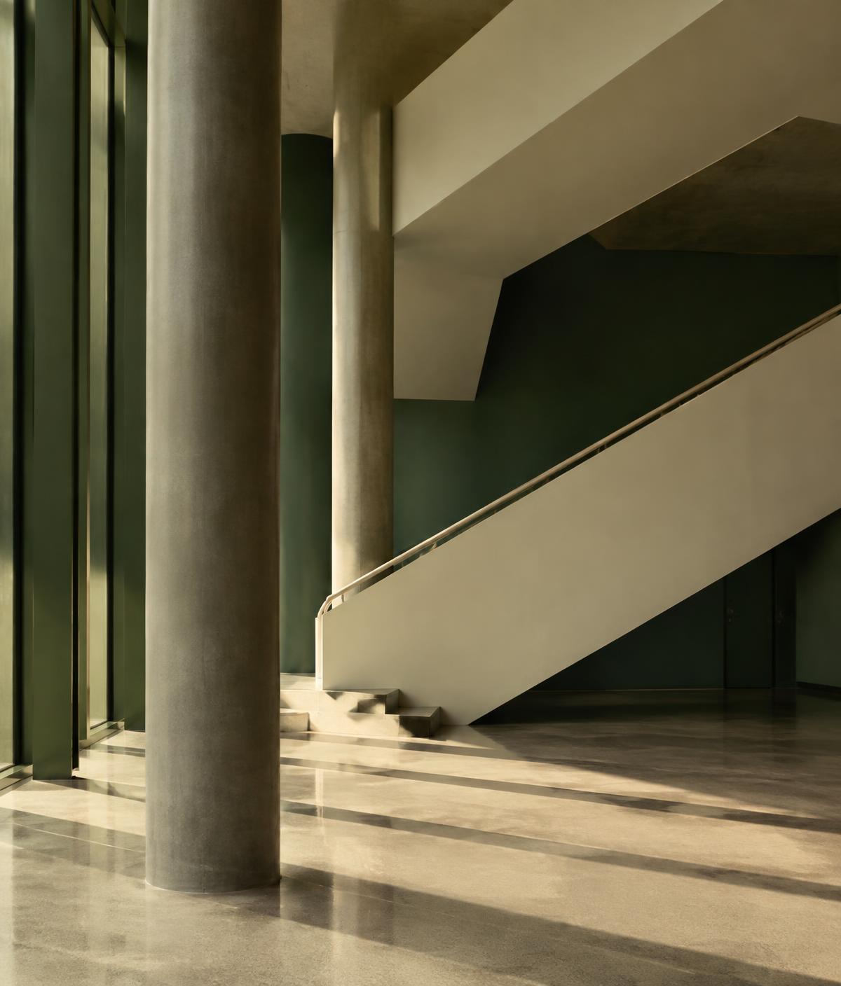 Quiet architectural interior with concrete columns and a staircase in warm light